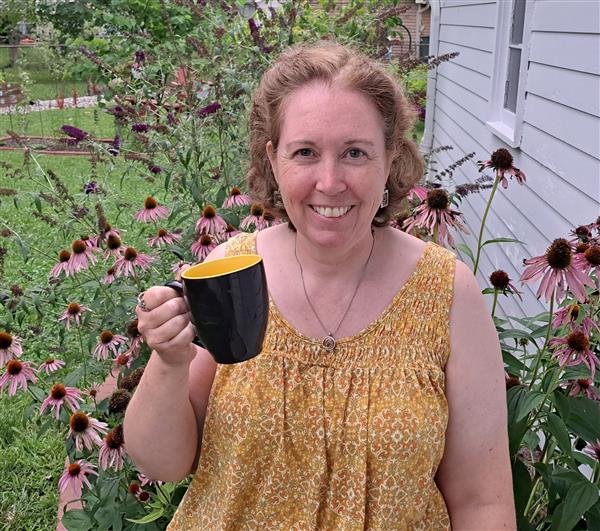 Ms. Kuenzel with coffee in her flower garden